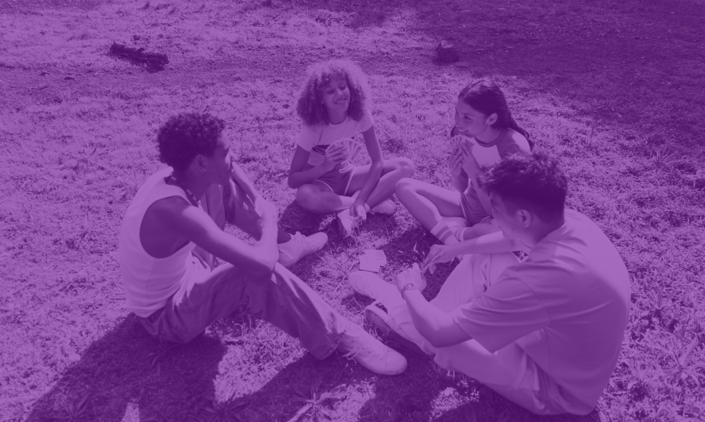 group of students playing cards on the grass during the summer holiday