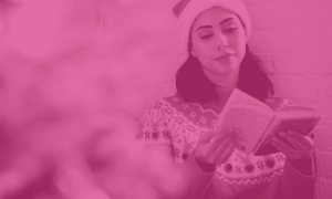 woman wearing christmas jumper and santa hat reading a book