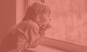 young boy looking out a window with his hand resting on his chin